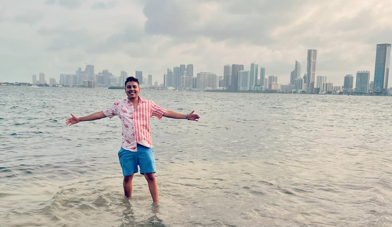 Julian Tavera standing in shallow water with a city skyline behind him
